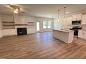 Open concept living room and kitchen with hardwood floors, a fireplace, a kitchen island with granite countertops, and modern appliances at 282 Trescott St, Smithfield, NC 27577