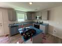 Modern kitchen with stainless steel appliances, gray cabinets, and granite countertops, great for cooking and entertaining at 33 W Emily Gardens Dr, Selma, NC 27576