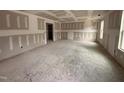 A spacious living room is under construction, featuring drywall, light fixtures, and an open doorway, flooded with natural light at 33 W Emily Gardens Dr, Selma, NC 27576