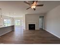 Bright, open living space with a modern ceiling fan, fireplace, and wood floors leading to the kitchen at 40 Tuskeegee Dr, Smithfield, NC 27577
