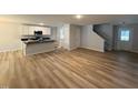 Open concept living space with hardwood floors, white kitchen cabinets, and staircase access at 41 W Emily Gardens Dr, Selma, NC 27576