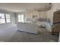 Kitchen with window, white cabinets, and island covered in protective plastic at 56 Bailey-Boykin Rd, Selma, NC 27576