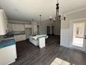 Spacious kitchen area with white cabinets, pendant lighting and a view of the dining and living areas at 612 Tuscany Cir, Princeton, NC 27569