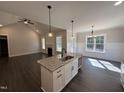 Open kitchen with granite island overlooking the living area, featuring dark wood floors and modern finishes at 612 Tuscany Cir, Princeton, NC 27569