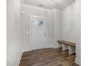 Welcoming entryway featuring a white door, convenient bench seating, and modern wood-look flooring at 613 Tuscany Cir, Princeton, NC 27569