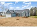 Single-story home with blue siding, a two-car garage and freshly laid lawn at 613 Tuscany Cir, Princeton, NC 27569