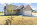 New home featuring a well-maintained lawn and charming exterior details, plus a young tree in the front yard at 68 Tee Dr, Selma, NC 27576