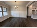 Bright dining room with wainscoting, hardwood floors, and modern chandelier at 702 Tuscany Cir, Princeton, NC 27569