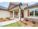 Inviting front porch with stone accents, a red front door, and well-maintained landscaping at 702 Tuscany Cir, Princeton, NC 27569