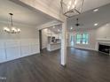 Spacious living room with elegant lighting, wood floors, and a cozy fireplace, flowing into the open kitchen at 702 Tuscany Cir, Princeton, NC 27569