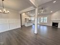 Open concept living area featuring hardwood floors, modern lighting, and fireplace with brick surround at 702 Tuscany Cir, Princeton, NC 27569
