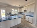 Bright kitchen featuring white cabinets, an island and stainless steel sink at 76 Royal Ave, Selma, NC 27576