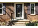 Close-up of the front door, featuring a brick facade, black shutters, and decorative iron railings at 7605 Mine Valley Rd, Raleigh, NC 27615