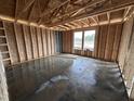 Framed bedroom with a view showcases stud walls, a large window overlooking the yard, concrete flooring, and exposed rafters at 8 W Emily Gardens Dr, Selma, NC 27577