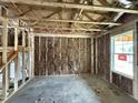 Unfinished living room features stud framing, insulation, and a window at 82 W Emily Gardens Dr, Selma, NC 27577