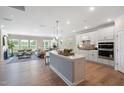 Open-concept kitchen with island, white cabinets, stainless appliances, and seamless flow to living area at 102 E Star Foal Ln, Wendell, NC 27591