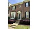 Charming brick townhouse with black shutters, white trim, a decorative wreath, and mature landscaping at 108 W Savannah Ridge Rd, Holly Springs, NC 27540
