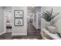 A hallway with dark wood floors, a decorative vase, artwork, and an open view into the adjacent living area at 153 Tennyson Dr # 235, Garner, NC 27529