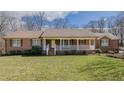 Charming red brick ranch-style home with white front porch, situated on a beautiful lawn at 1635 Sandy Cross Rd, Burlington, NC 27217