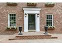 Close up of a brick home's main entrance with black door, flower boxes, and black urns at 2004 Riverview Dr, Clayton, NC 27527