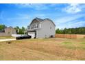 Side view of a gray two-story home with a spacious yard and a two-car garage at 211 Tobacco Barn Dr, Angier, NC 27501