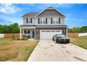 Charming two-story home features a gray facade, inviting front porch, and a two-car garage at 211 Tobacco Barn Dr, Angier, NC 27501