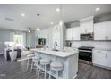 Modern kitchen with an island, pendant lights, and stainless steel appliances that opens to the living room at 355 Fosterton Cottage Way, Raleigh, NC 27603