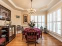 Formal dining room featuring hardwood floors, wainscoting, shuttered windows, elegant lighting, and classic decor at 4203 Norman Ridge Ln, Raleigh, NC 27613