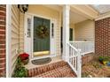 This covered front porch boasts a decorative wreath and space for potted plants at 4709 Knights Arm Dr, Durham, NC 27707