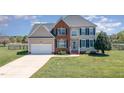 Inviting two-story home with a well-maintained lawn and a charming picket fence in the background at 4905 Homestead Dr, Mebane, NC 27302