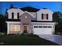 Charming two-story home with a stone facade, two-car garage, and professionally landscaped yard at 709 Deschutes Dr, Garner, NC 27529