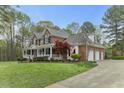 Charming brick home with a long, covered porch, attached three-car garage, and lush green lawn at 7336 Barham Hollow Dr, Wake Forest, NC 27587