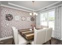 Elegant dining room featuring a patterned accent wall, stylish chandelier, and a modern wooden table at 105 Smoky Emerald Way, Holly Springs, NC 27540