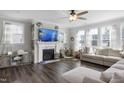 Inviting living room with hardwood floors, a fireplace, ceiling fan and ample natural light from multiple windows at 105 Smoky Emerald Way, Holly Springs, NC 27540