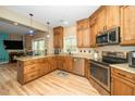 Well-lit kitchen with granite countertops, stainless steel appliances, wood cabinets, and hardwood floors, with a view to living room at 1114 Glenolden Ct, Cary, NC 27513