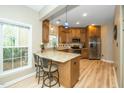 Bright kitchen features granite countertops, stainless steel appliances, island with bar seating, and wooden cabinets at 1114 Glenolden Ct, Cary, NC 27513