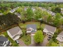 Aerial view of a two-story brick home with a well-maintained lawn, surrounded by mature trees in a quiet neighborhood at 112 Mendells Dr, Holly Springs, NC 27540