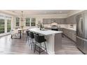 Modern kitchen with a large island, grey cabinets, stainless steel appliances, and adjacent dining area at 112 Mendells Dr, Holly Springs, NC 27540