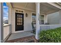 Inviting front porch featuring a classic black door and comfortable rocking chairs at 115 Windy Creek Ln, Apex, NC 27502