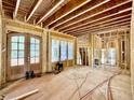 An unfinished room with exposed wood framework, large glass doors and windows offering ample natural light at 1218 Kingwood Dr, Raleigh, NC 27609