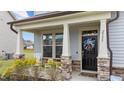 Inviting front porch with rocking chairs, stone accents, and a charming front door with seasonal wreath at 2157 Blue Iris Way, Zebulon, NC 27597