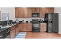 Well-lit kitchen features wooden cabinets, black appliances, sink and dark countertops at 228 Dove Cottage Ln, Cary, NC 27519