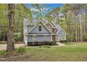 Two-story home nestled in trees with blue siding, a stone facade, and manicured landscaping at 250 Highview Dr, Youngsville, NC 27596