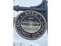 Round sign indicating the Apex Historic District with a vintage building illustration at 311 Culvert St, Apex, NC 27502