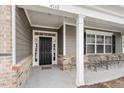 Inviting covered porch with seating, brick accents, and stylish front door, enhancing curb appeal at 4712 Bright Pebble Ct, Raleigh, NC 27604