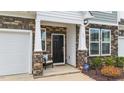Cozy front porch with stone accents, a black front door, and an ADT security system at 53 Whitley Ridge Dr, Clayton, NC 27527