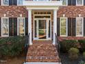 Inviting front entrance with brick steps, white columns, and a glass storm door at 5816 Sand Pebble Pl, Raleigh, NC 27613