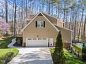 Side view of home showing a two-car garage, concrete driveway and mature trees at 5816 Sand Pebble Pl, Raleigh, NC 27613