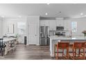Bright open-concept kitchen featuring white cabinets, stainless steel appliances, and a large island with seating at 6309 Truxton Ln, Raleigh, NC 27616