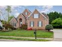 Charming brick home with a lush front lawn, mature trees, and tidy landscaping at 9201 Club Hill Dr, Raleigh, NC 27617